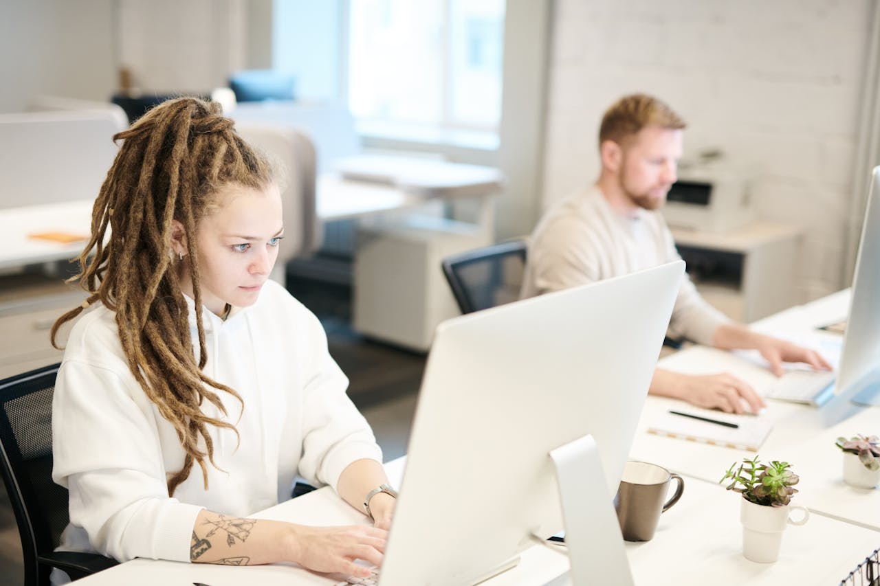 Two colleagues concentrating on work, using computers in a bright modern office.