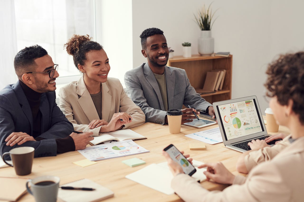 Young professionals discussing work at a conference table with technology and documents.